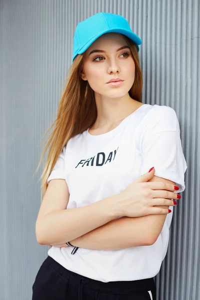 회색 벽의 배경에 파란색 모자에 아름다운 금발소녀 — 스톡 사진