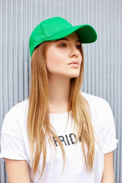 Piękna blond dziewczyna w zielonej czapce na tle szarej ściany — Zdjęcie stockowe