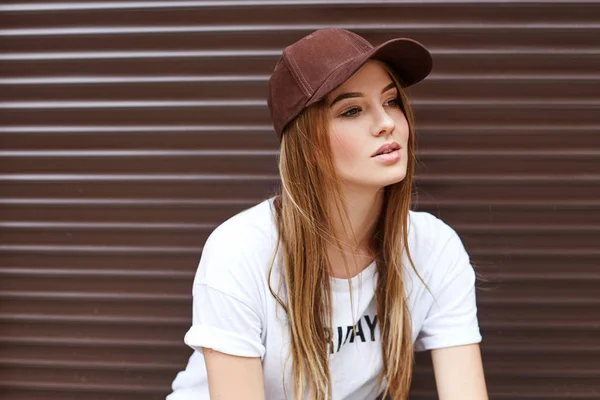 Hermosa chica rubia en una gorra marrón sobre un fondo de pared —  Fotos de Stock