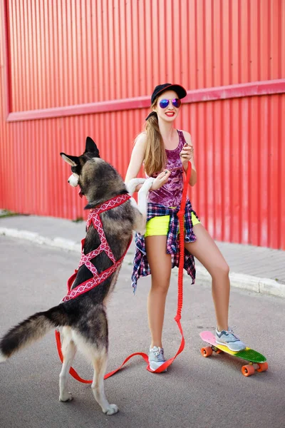 Girl on a skateboard with a dog — Stock Photo, Image