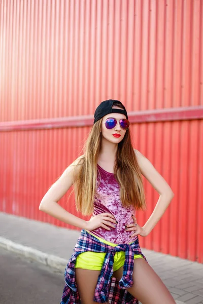 Chica con un monopatín sobre un fondo de pared roja —  Fotos de Stock
