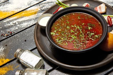 Borsch ekşi krema, soğan ve koyu bir arka plan üzerinde bir topuz ile