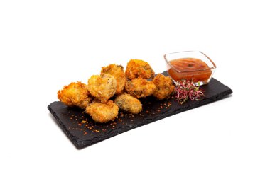 Beyaz arka planda izole edilmiş taş bir tabakta soslu kızarmış rapanlar.