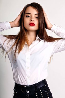 Kot pantolon giymiş genç bir kız ve stüdyoda beyaz arka planda bir gömlek.