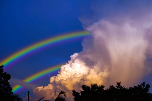 Arco-íris aparece no céu após a chuva e de volta ao pôr do sol clo — Fotografia de Stock