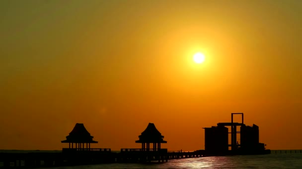 Zonsondergang oranje wolk en silhouet twee verlaten paviljoen in zee — Stockvideo