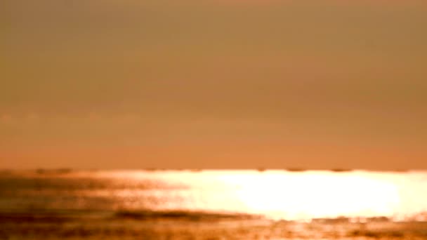 Riflesso sfocato colore arancione della luce del sole sulla superficie del mare e piccola onda in movimento — Video Stock