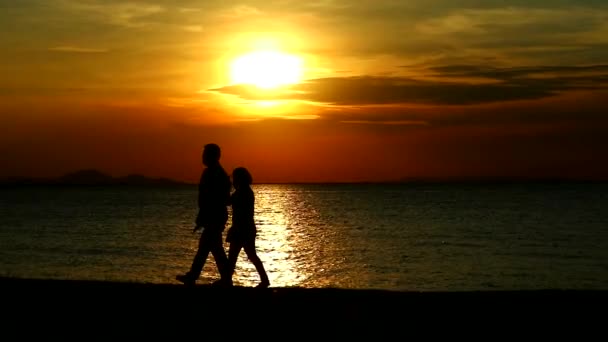 Ζευγάρι εραστής περπάτημα στην παραλία, ενώ το ηλιοβασίλεμα στη θάλασσα — Αρχείο Βίντεο