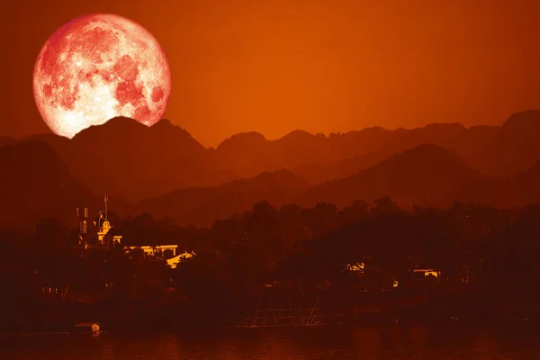 Luna de sangre en la noche cielo rojo de vuelta sobre la silueta montaña — Foto de Stock