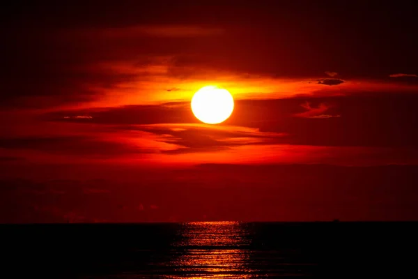 Deniz ve okyanus geçen ışık kırmızı gökyüzü siluet bulut on Sunset