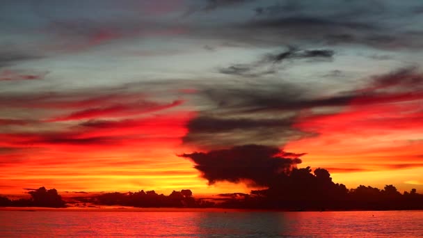 Rudý plamen slunce na oranžovém nebi a temně rudé siluetě na moři — Stock video