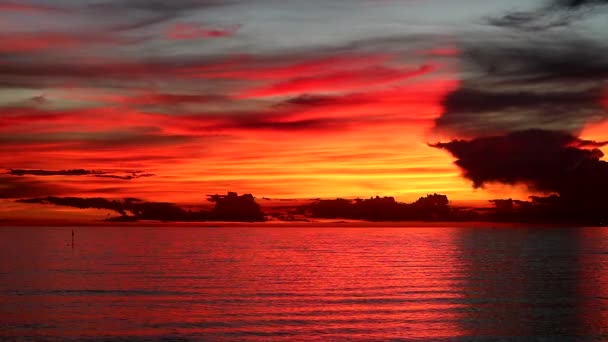 Puesta de sol de llama roja en el cielo naranja y nube de silueta roja oscura en el mar — Vídeos de Stock