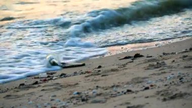 plastik cam ve atık ile denizde gün batımı sahilde bırakılır ve dalgalar denize onları uçurdu2