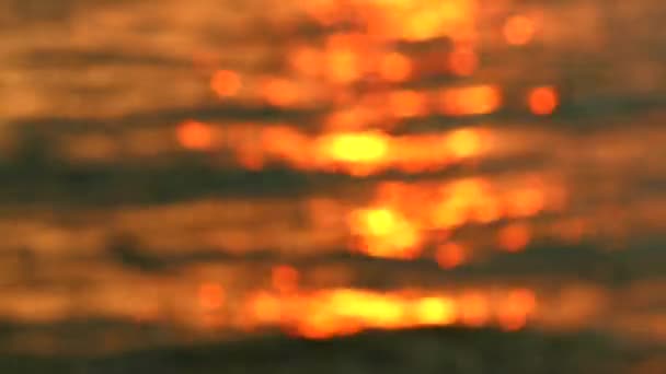 夕日の反射赤黄色、海のぼかしカラフルな表面に波水 — ストック動画