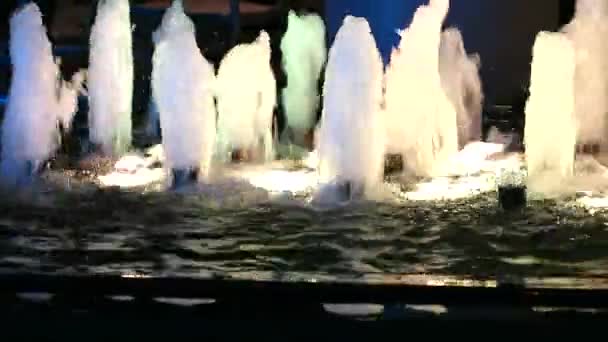Panorámica de la fuente de agua en la superficie de la piscina con luz nocturna — Vídeos de Stock