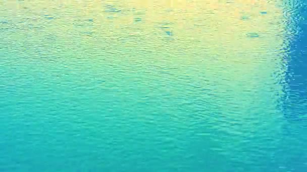 Rain fall on blue pure and clear water surface and reflection of sunset — Stock Video