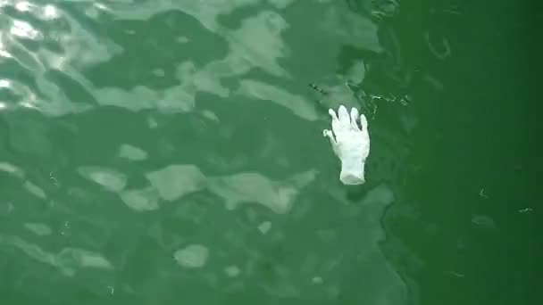 Guante de goma flotando en la superficie del agua del mar — Vídeo de stock