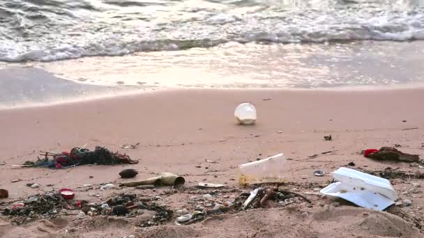 Coucher de soleil sur la mer avec du plastique et des déchets sur la plage et les vagues les ont soufflés dans la mer — Video