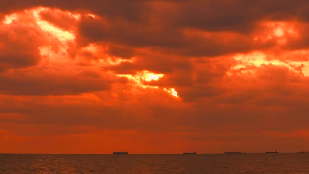 Pôr-do-sol laranja céu amarelo nuvem tempestade vermelha em movimento no mar e silhueta navio de carga e barco de pesca em movimento — Vídeo de Stock