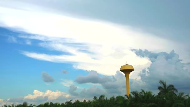 Żółty zbiornik na wodę i chmura porusza się nad zielonym ogrodem kokosowym — Wideo stockowe