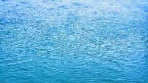 Lluvia cae sobre la superficie azul de agua pura y clara — Vídeos de Stock