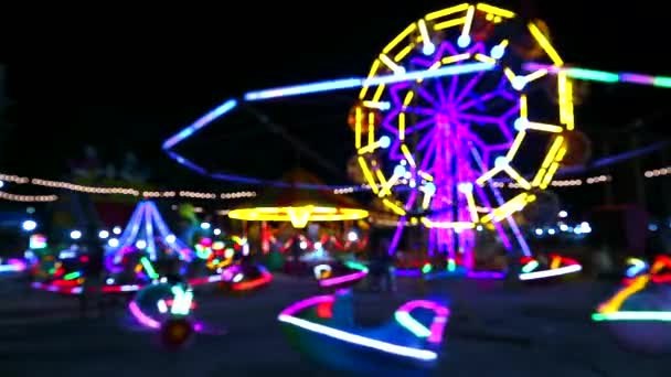 Mehrfarbiges Riesenrad und rollendes Neonlicht auf dem Nachtmarkt verschwimmen — Stockvideo