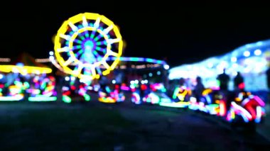 Gece pazarı fuarında atlıkarınca ve dönme dolap ve neon tren ışığı