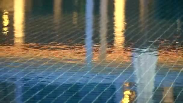 Chuva cair na piscina e reflexão da luz sobre a superfície da água — Vídeo de Stock