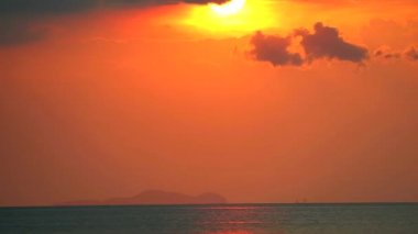 Gün batımı deniz silueti. Koyu kırmızı bulut hareket ediyor. Güneşi geçiyor.