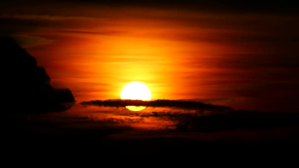 Sonnenuntergang auf dunkelroter Wolke und orangefarbenem Himmel und Silhouettenflugzeug fliegen im Zeitraffer an der Sonne vorbei — Stockvideo