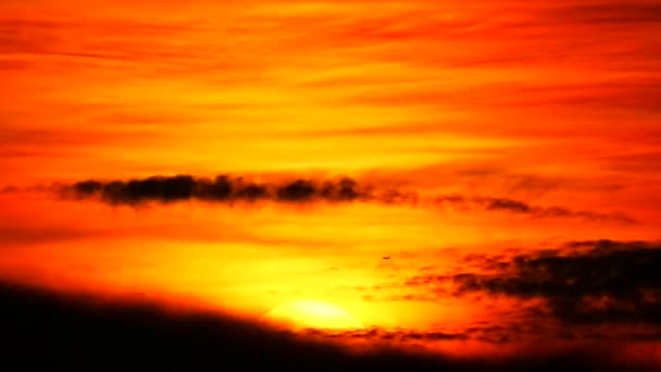 Zachód słońca na ciemnoczerwonej chmurze i pomarańczowym niebie i sylwetka samolotu lecącego mijać słońce 1 — Wideo stockowe