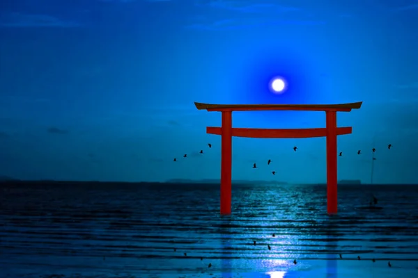 full moon over torii on night sky and silhouette birds flying on the sea