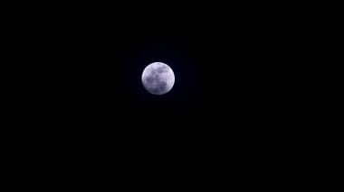 Gece gökyüzünde dolunay yükseliyor ve beyaz bulut hareket ediyor.