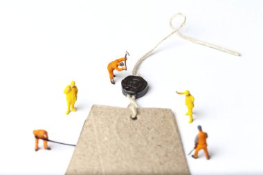 Moda endüstrisi için kavram. Giysi etiketi ile minyatür kişi çalışıyor. Yakın çekim.