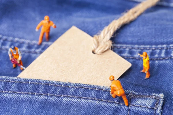 The concept for the fashion industry. Miniature workers on denim texture. Close up.