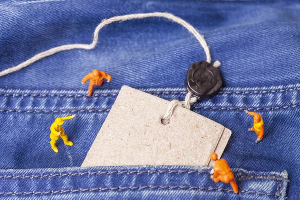 The concept for the fashion industry. Miniature workers on denim texture. Close up.