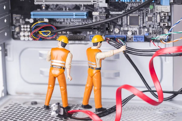 The concept of error correction or repair your computer. Miniature toy engineers fixing error on motherboard. Close-up view.