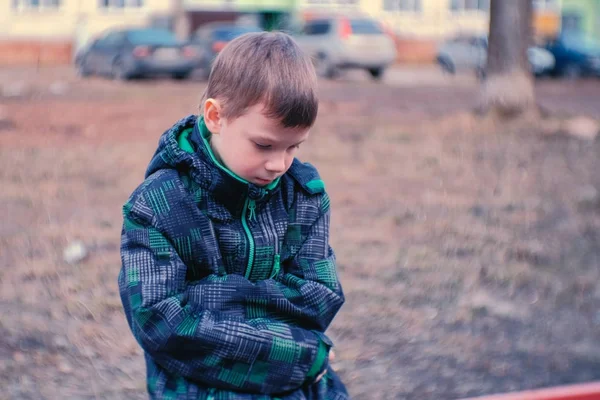 Rapaz triste sentado num banco. Menino está perdido e esperando pelos pais . — Fotografia de Stock