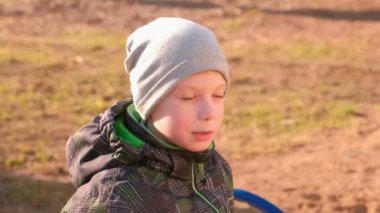 Çocuk parkta bankta oturur ve konuşuyor.