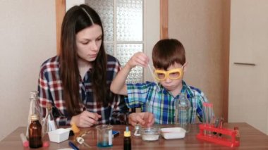 Evde kimya üzerinde deneyler. Anne ve oğlu birlikte bilimsel bir deney yapmak.
