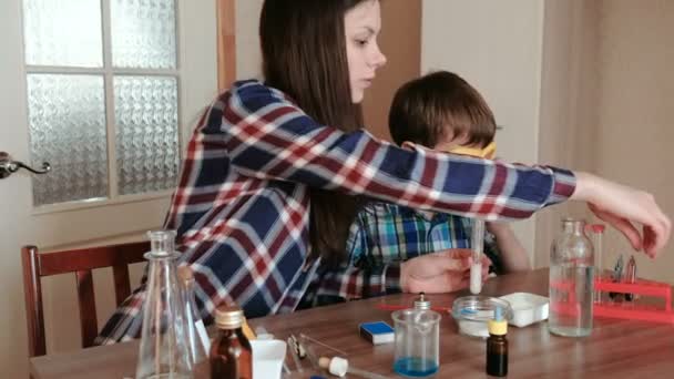 Expériences de chimie à la maison. Maman et son fils font une réaction chimique avec la libération de gaz dans le tube à essai . — Video