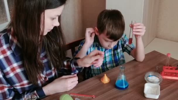 Scheikundige experimenten thuis. Moeder en zoon maken een chemische reactie met de release van gas in de kolf. — Stockvideo