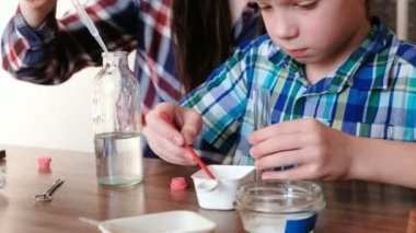 Kimya deneyleri evde. Anne ve oğlu bir test tüpü içinde çeşitli maddeler eklemek.