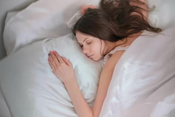 Μελαχρινή νεαρή γυναίκα στον ύπνο στο κρεβάτι. — Φωτογραφία Αρχείου