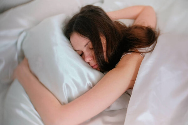 Young woman brunette sleeping in bed.