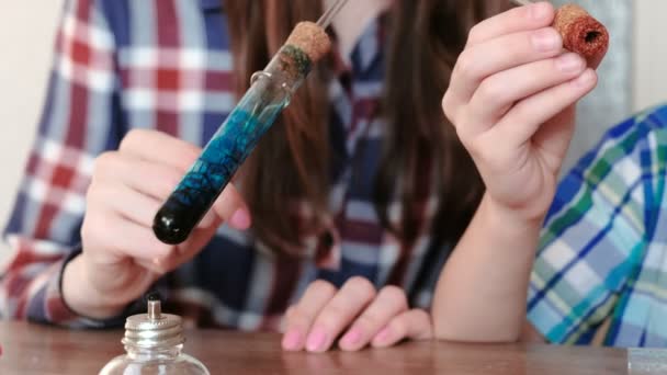 Expériences en chimie à la maison. Garçon et sa mère chauffent le tube à essai avec du liquide bleu sur la lampe à alcool brûlante. Le liquide bout en gros plan . — Video