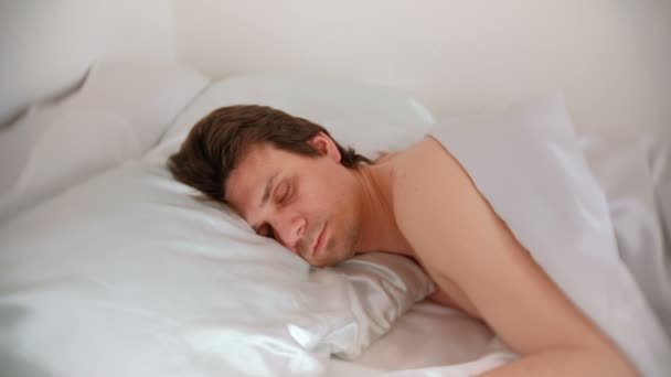 Člověk spí v posteli sám pod dekou. Boční pohled. — Stock video