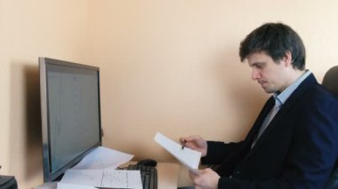 Adam bir bilgisayarda çalışıyor. Grafik kağıt üzerinde inceden inceye gözden geçirmek.