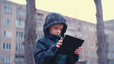 Çocuk bahçesinde içinde bankta parkta oturmuş onun tablet Internet tarama.
