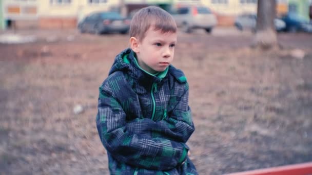 Сумний хлопець сидить на лавці. Хлопчик загубився і чекає батьків . — стокове відео